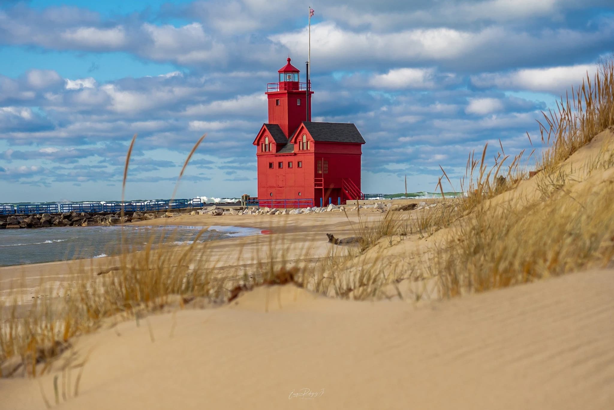 A red lighthouse on the Lake Michigan shoreline in West Michigan