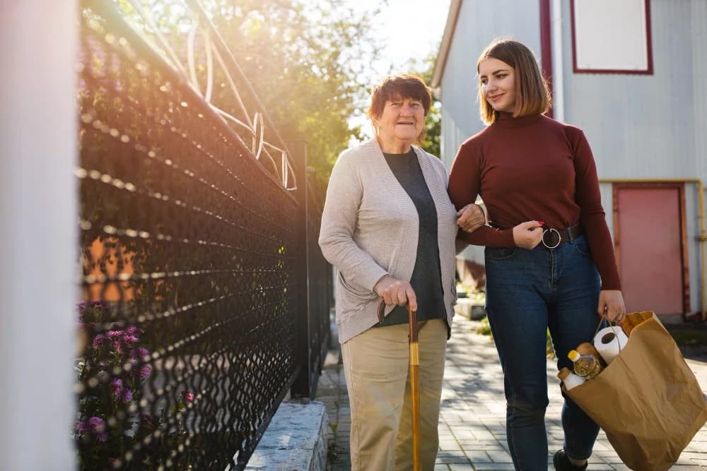 A caregiver walking outside with an older adult