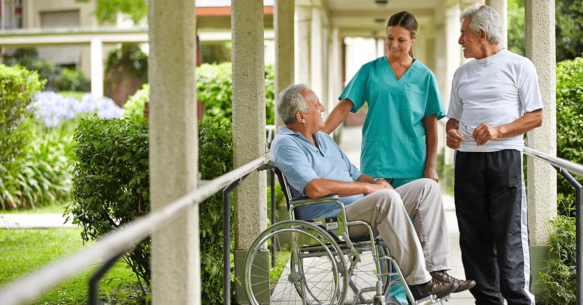 A caregiver talking with two older adults outdoors